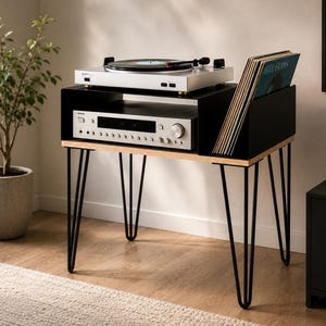 Può includere: Un mobiletto per giradischi in legno chiaro e nero con quattro gambe a forcina in metallo nero. L'unità presenta una superficie superiore per un giradischi, un ripiano centrale per un ricevitore audio e uno scomparto laterale per i vinili.