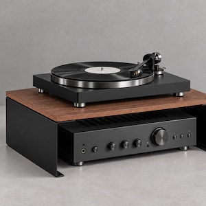 May include: A black metal audio equipment stand with a dark wood grain top surface. A black turntable with a vinyl record sits on top, while a black audio amplifier with multiple circular control knobs and a headphone jack is placed underneath.