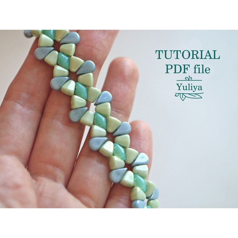 Peut inclure: Un bracelet fait &agrave; la main avec un motif r&eacute;p&eacute;titif de perles en forme de goutte d'eau dans des tons de vert et de bleu. Le bracelet est tenu dans une main, mettant en valeur son design complexe. L'image comprend le texte "TUTORIAL PDF file" et le nom "Yuliya".