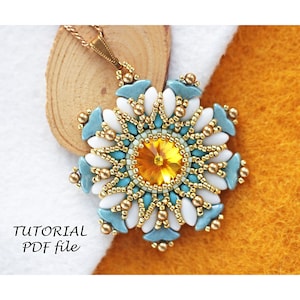 May include: A beaded pendant necklace with a gold chain and a large, multi-coloured flower design. The flower is made of white, blue, and gold beads and has a yellow crystal in the centre. The pendant is on a wooden surface.