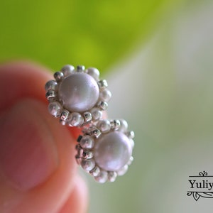 May include: A pair of pearl earrings with a silver setting. The pearls are white and round, and the setting is made of small silver beads.