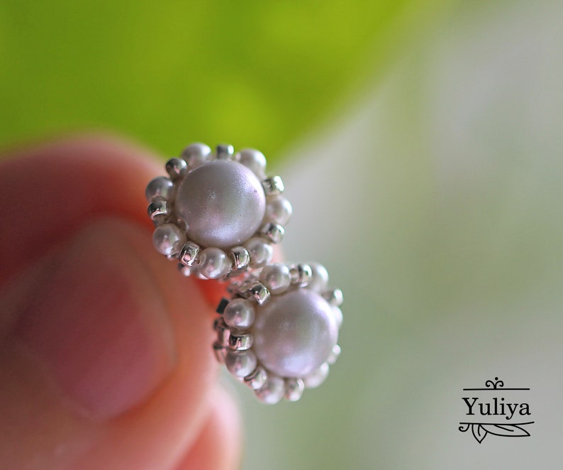 May include: A pair of pearl earrings with a silver setting. The pearls are white and round, and the setting is made of small silver beads.