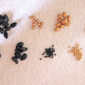 Peut inclure: Assortiment de perles noires et dor&eacute;es, comprenant des formes en goutte, rondes et facett&eacute;es. Sont &eacute;galement inclus deux anneaux de jonction dor&eacute;s et un fermoir dor&eacute;.