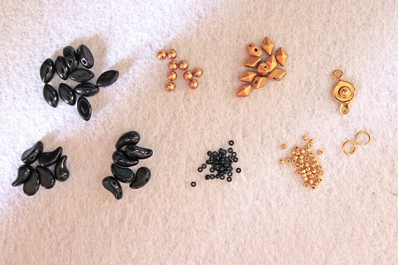 Peut inclure: Assortiment de perles noires et dor&eacute;es, comprenant des formes en goutte, rondes et facett&eacute;es. Sont &eacute;galement inclus deux anneaux de jonction dor&eacute;s et un fermoir dor&eacute;.