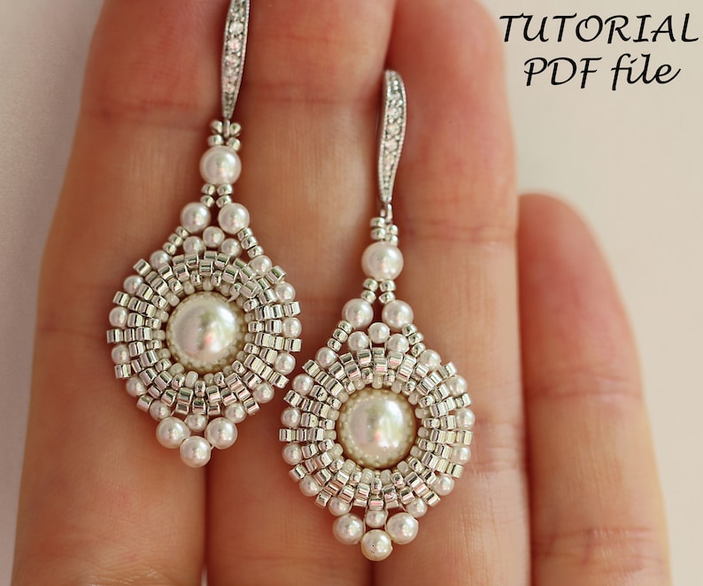 Może przedstawiać: Para srebrnych i białych koralikowych kolczyk&oacute;w z perłą w środku każdego kolczyka. Kolczyki są wiszące i mają kształt łzy. Obraz zawiera tekst "TUTORIAL PDF file".