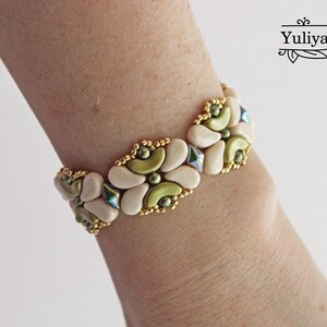 Op de afbeelding: Een witte en groene kralen armband met gouden accenten. De armband is gemaakt van kleine, ronde kralen en heeft een bloemmotief.