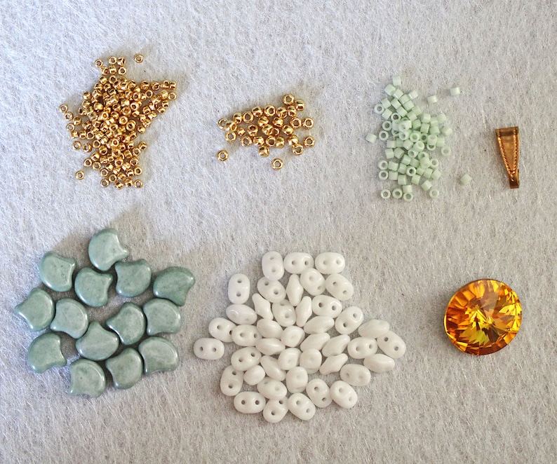 May include: Assortment of beads in various colors and shapes, including gold, white, and light green. There is also a single, large, orange crystal bead.