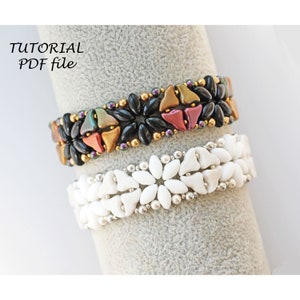 Pode incluir: Duas pulseiras de contas, uma com contas pretas, douradas e multicoloridas, e a outra com contas brancas. As pulseiras estão sobre uma superfície cinza.  "TUTORIAL PDF file" está escrito em preto na superfície.