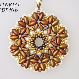 May include: A gold, brown, and white beaded pendant with a circular design. The pendant is made with seed beads and pearls.