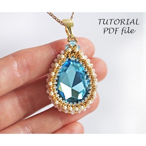 May include: A blue crystal pendant with gold and white beads, hanging from a gold chain. The pendant is in the shape of a teardrop and has a faceted design. The image includes the text "TUTORIAL PDF file".