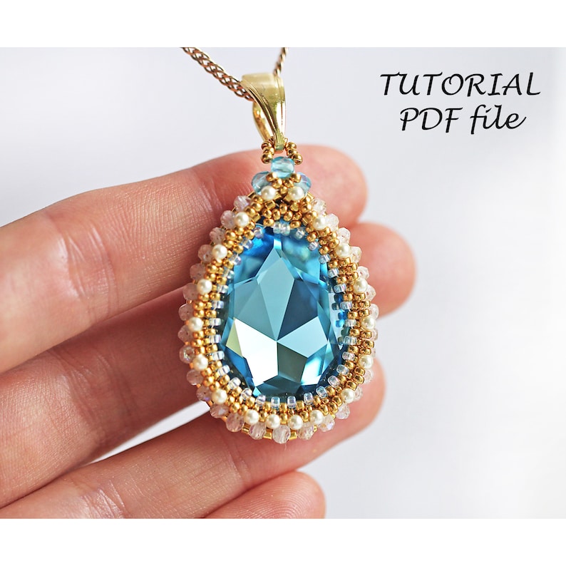 Peut inclure: Un pendentif en cristal bleu avec des perles dor&eacute;es et blanches, suspendu &agrave; une cha&icirc;ne dor&eacute;e. Le pendentif a la forme d'une larme et pr&eacute;sente un design facett&eacute;. L'image comprend le texte "TUTORIAL PDF file".