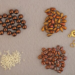 Peut inclure: Assortiment de perles brunes, dor&eacute;es et blanches pour la fabrication de bijoux. Les perles sont de formes et de tailles vari&eacute;es, notamment rondes, en forme de larme et en perles de rocaille. Il y a &eacute;galement un fermoir en m&eacute;tal dor&eacute;.