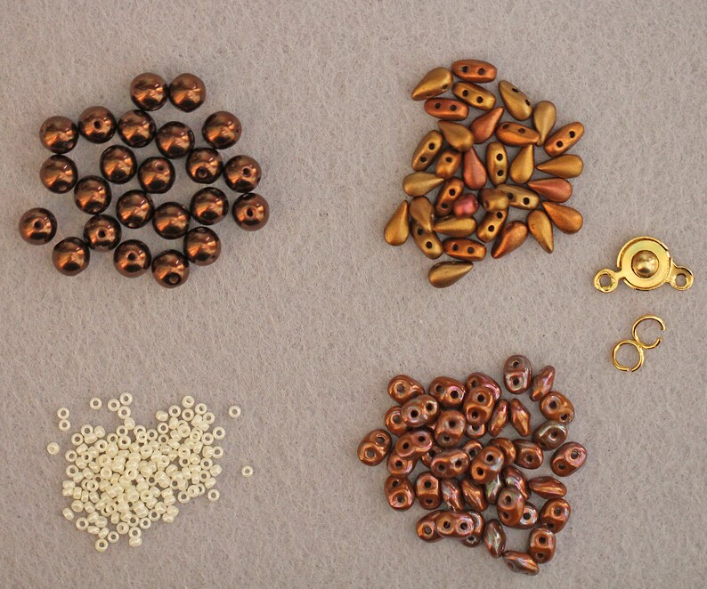 Peut inclure: Assortiment de perles brunes, dor&eacute;es et blanches pour la fabrication de bijoux. Les perles sont de formes et de tailles vari&eacute;es, notamment rondes, en forme de larme et en perles de rocaille. Il y a &eacute;galement un fermoir en m&eacute;tal dor&eacute;.