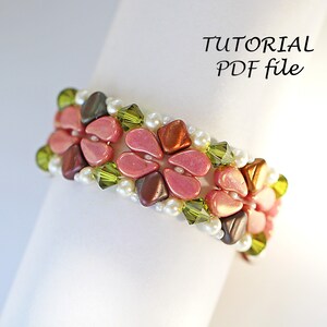 May include: A beaded bracelet with pink, brown, and green beads in a floral pattern. The bracelet is on a white surface with the text "TUTORIAL PDF file".