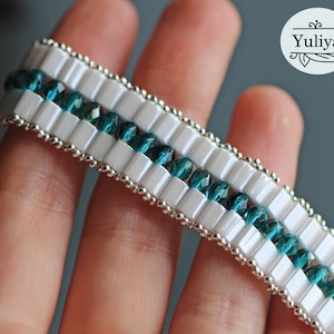 May include: A white and teal beaded bracelet with silver beads separating the rows of beads.