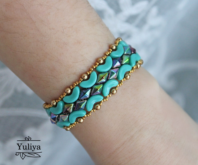 May include: A turquoise and gold beaded bracelet with a geometric pattern. The bracelet is made with small, round beads and larger, crescent-shaped beads.