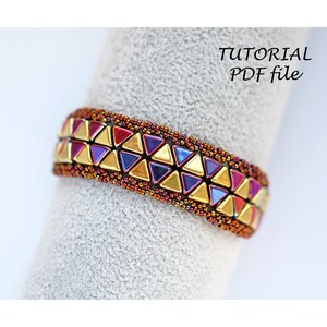 May include: A beaded bracelet with a geometric pattern of gold, purple and red triangles. The bracelet is on a grey surface.  "TUTORIAL PDF file" is written in black text on a white background.