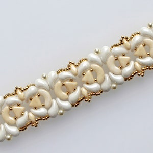 Op de afbeelding: Een witte en cr&egrave;mekleurige kralenarmband met een delicaat bloemenpatroon. De armband is gemaakt van kleine, ronde kralen en heeft een herhalend patroon van bloemen.