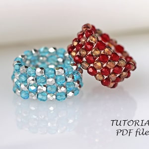 May include: Two beaded rings, one blue and silver, the other red and gold. The rings are stacked on top of each other. The text "TUTORIAL PDF file" is visible below the rings.