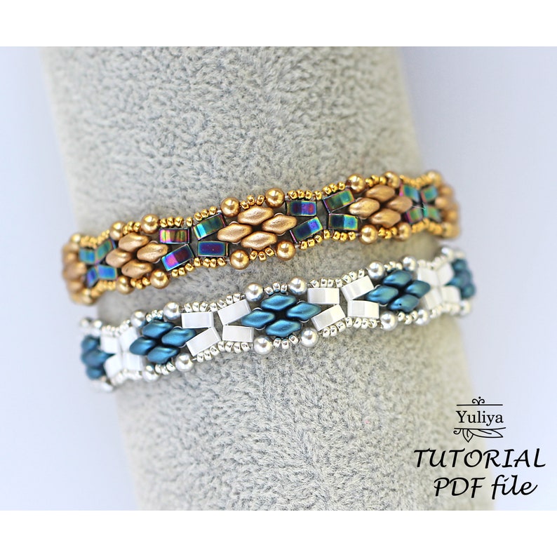 Op de afbeelding: Twee kralenarmbanden, een met gouden en regenboogkleurige blauwe kralen, de andere met teal, witte en zilveren kralen. De armbanden liggen op een grijs oppervlak. De tekst "Tutorial PDF file" staat onder de armbanden.
