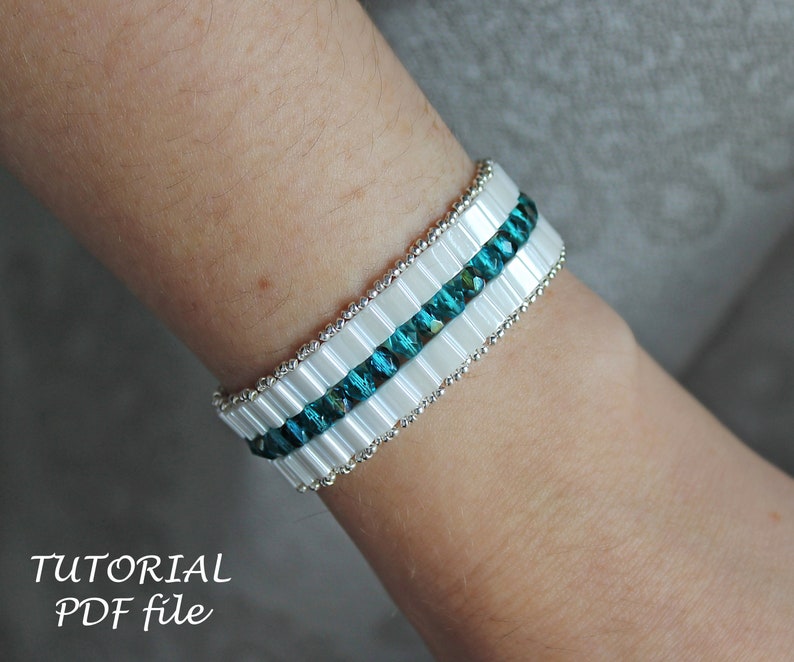 May include: A white and teal beaded bracelet with a silver accent. The bracelet is on a person's wrist.  TUTORIAL PDF file