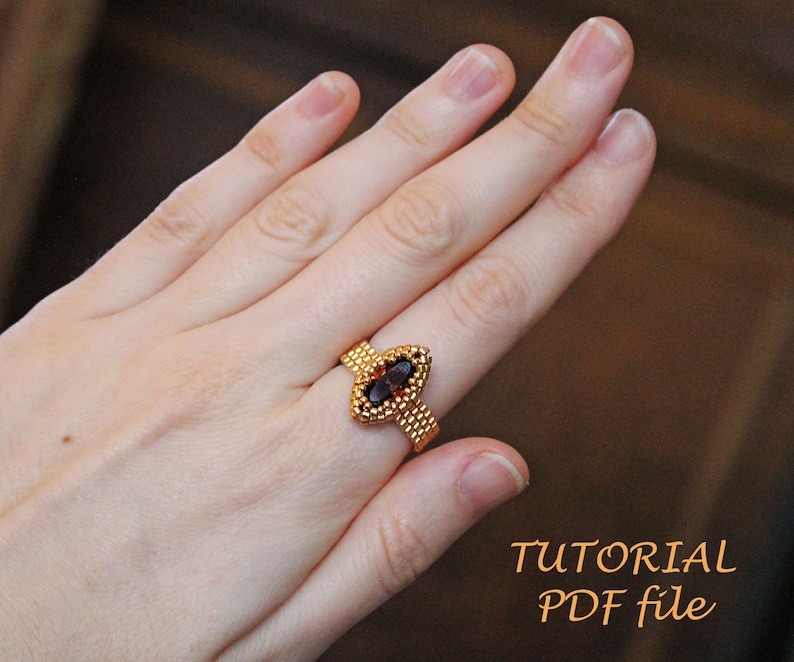 K&ouml;nnte beinhalten: Ein goldfarbener Perlenring mit einem dunkelbraunen ovalen Edelstein. Der Ring befindet sich an einem Finger. Das Bild enth&auml;lt den Text "TUTORIAL PDF file".