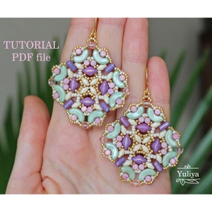 Puede incluir: Un par de pendientes de oro con un diseño geométrico hecho con cuentas en tonos de rosa, verde y morado. Los pendientes están hechos a mano y tienen un diseño delicado e intrincado.