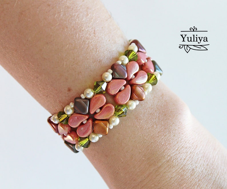 May include: A pink, brown, and green beaded bracelet with a floral design. The bracelet is made with small, faceted beads and is worn on a person's wrist.