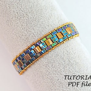 May include: A beaded bracelet with a geometric pattern in shades of blue, gold, and iridescent colors. The bracelet is made with small square beads and is finished with gold-colored beads.