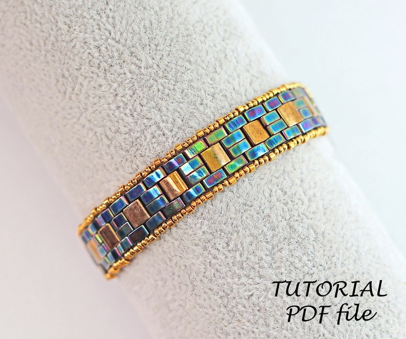 May include: A beaded bracelet with a geometric pattern in shades of blue, gold, and iridescent colors. The bracelet is made with small square beads and is finished with gold-colored beads.