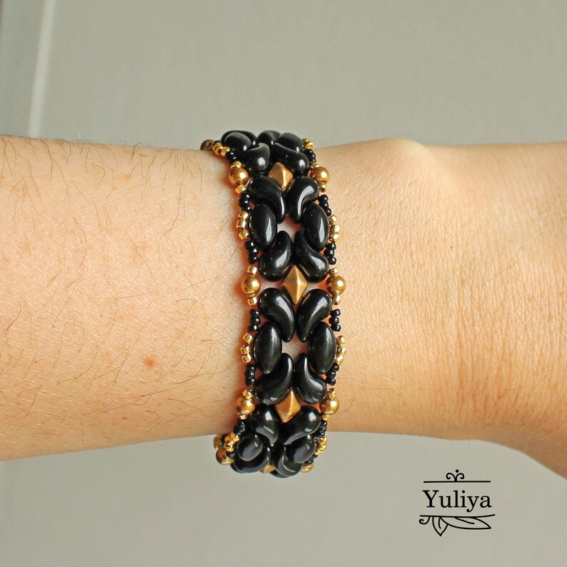Peut inclure: Bracelet en perles noires et dor&eacute;es avec un motif g&eacute;om&eacute;trique. Le bracelet est compos&eacute; de petites perles rondes et de perles plus grandes en forme de goutte.