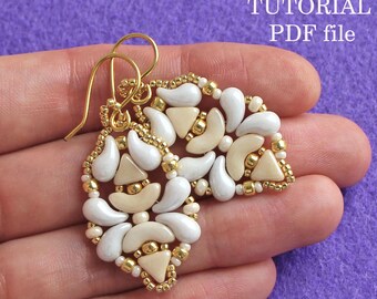May include: A pair of gold and white beaded earrings with a geometric design. The earrings are handmade and feature a variety of beads, including small gold beads and larger white beads. The earrings are attached to gold hooks.