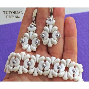 May include: A set of white and silver beaded earrings and a bracelet. The earrings and bracelet feature a repeating pattern of white and silver beads, with a single pearl bead in the center of each flower-shaped design. The image includes the text "TUTORIAL PDF file".