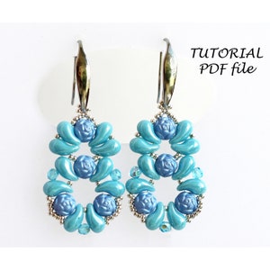 May include: A pair of blue and silver earrings with a floral design. The earrings are made with small beads and have a teardrop shape. The earrings are hanging from silver hooks.