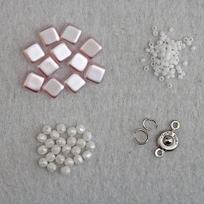 May include: A set of jewelry making supplies including pink square beads, white round beads, and a silver clasp with the text "Tang Yue".
