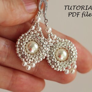 Może przedstawiać: Para srebrnych kolczyk&oacute;w z białymi perłami i koralikowym wzorem. Kolczyki mają dużą perłę w środku każdego kolczyka. Kolczyki wiszą na srebrnym haczyku. Obraz zawiera tekst "TUTORIAL PDF file".