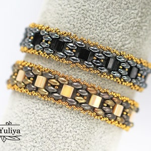 Puede incluir: Dos pulseras de cuentas, una con cuentas negras y plateadas y la otra con cuentas doradas, marrones y crema.