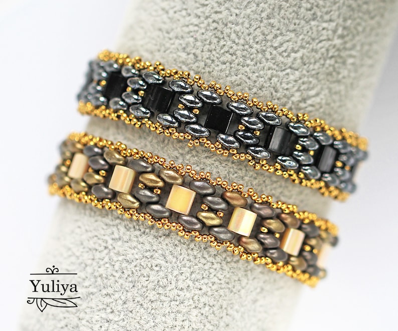 Puede incluir: Dos pulseras de cuentas, una con cuentas negras y plateadas y la otra con cuentas doradas, marrones y crema.
