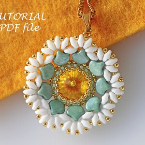 May include: A beaded pendant with a gold chain, featuring a circular design with a yellow center surrounded by green and white beads. The pendant is on a yellow fuzzy surface. The text "TUTORIAL PDF file" is in the top left corner of the image.