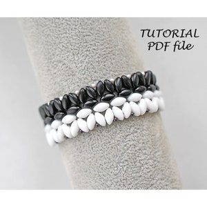 Op de afbeelding: Close-up van drie kralenarmbanden in zwart en wit. De armbanden zijn gemaakt van kleine, ovaalvormige kralen. De tekst "TUTORIAL PDF file" staat in de rechterbovenhoek. De armbanden worden op een grijze ondergrond getoond.