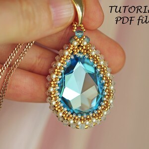 Peut inclure: Un collier avec un pendentif en forme de larme compos&eacute; d'un grand cristal bleu entour&eacute; de perles dor&eacute;es et blanches. Le collier est sur une cha&icirc;ne dor&eacute;e. L'image comprend le texte "TUTORIAL PDF file".