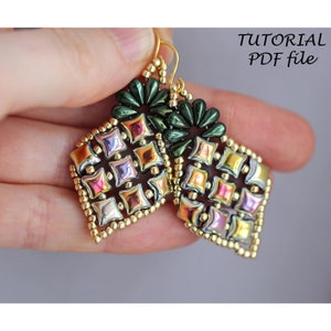 Puede incluir: Un par de pendientes de cuentas doradas e iridiscentes con un diseño geométrico. Los pendientes tienen forma de diamante y presentan una variedad de colores, incluyendo verde, rosa y dorado. Los pendientes se sostienen en una mano, y el texto "TUTORIAL PDF file" es visible en la esquina superior derecha de la imagen.