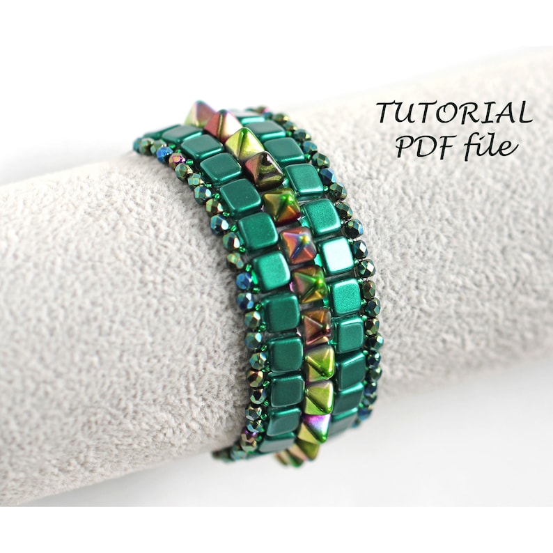 May include: A green and iridescent beaded bracelet with a geometric pattern. The bracelet is made with square and triangular beads.  "TUTORIAL PDF file" is written in white text on a black background.
