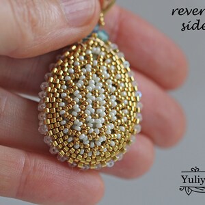 Peut inclure: Gros plan sur l'arri&egrave;re d'un pendentif en forme de larme en perles dor&eacute;es et blanches. Les perles sont dispos&eacute;es en cercle, cr&eacute;ant un motif textur&eacute; et complexe.