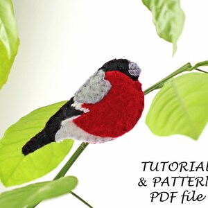 May include: A red and black felt bird with a white belly perched on a green leaf branch. The text "TUTORIAL & PATTERN PDF file" is below the bird.