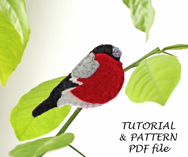 May include: A red and black felt bird with a white belly perched on a green leaf branch. The text "TUTORIAL & PATTERN PDF file" is below the bird.