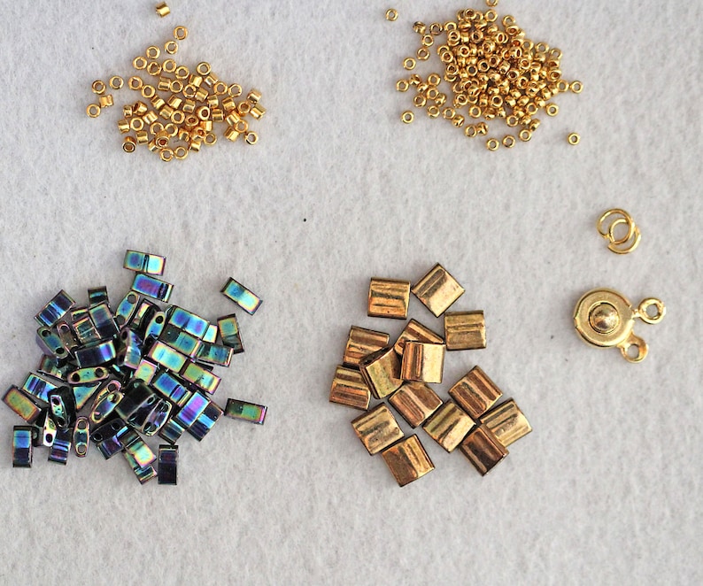 May include: Assortment of gold and iridescent beads, including round, square, and rectangular shapes. Also included are two gold metal clasps.