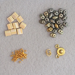 Puede incluir: Surtido de cuentas de varias formas y colores, incluyendo dorado, marr&oacute;n y beige. Tambi&eacute;n hay dos cierres de metal dorado.