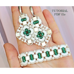 May include: A set of white and green beaded earrings and a bracelet. The earrings and bracelet feature a geometric design with square and crescent-shaped beads. The beads are silver, white, and green. The image includes the text "TUTORIAL PDF file".