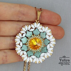 May include: A white and green beaded pendant necklace with a yellow crystal in the center. The pendant is in the shape of a flower.